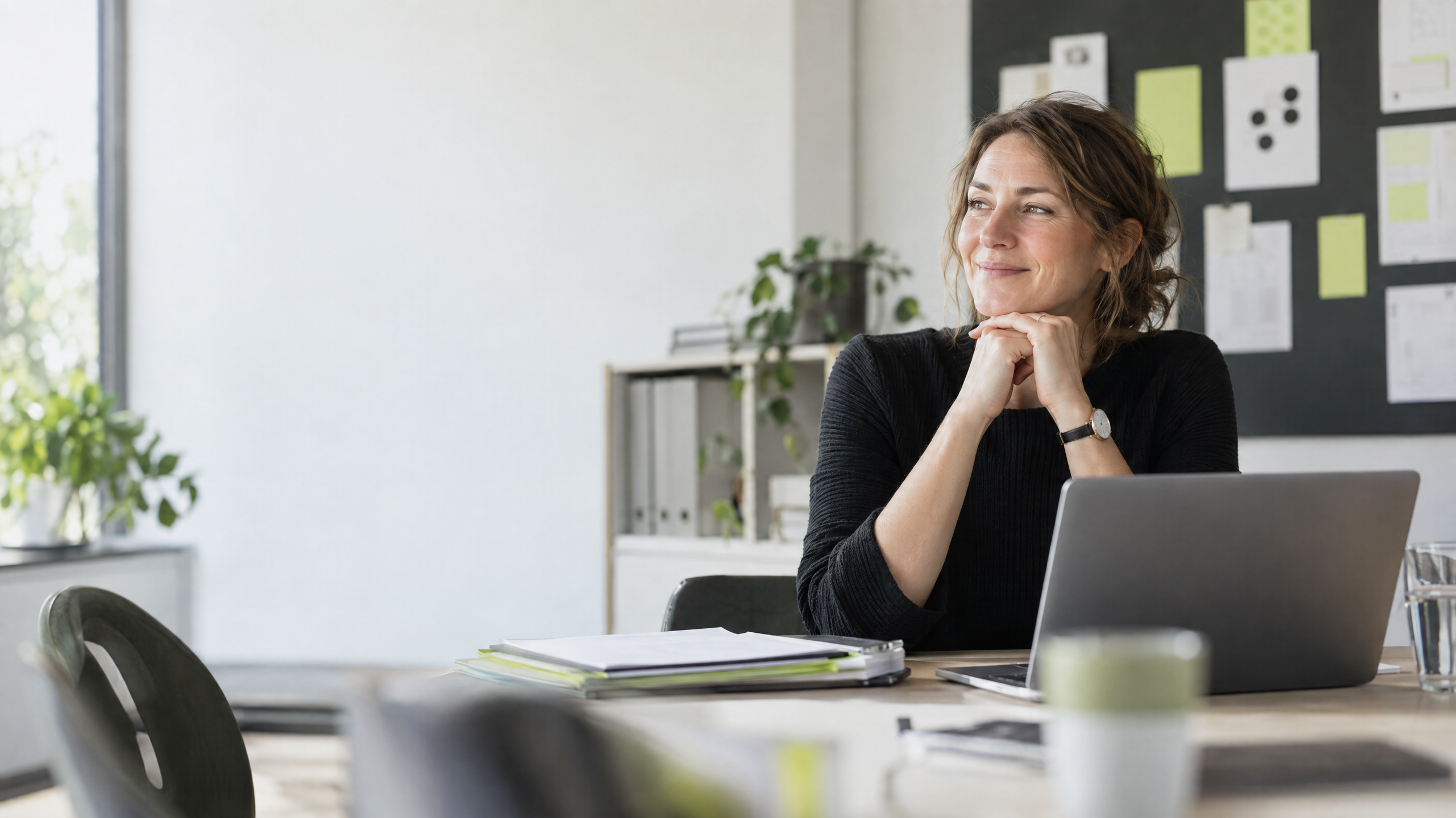 Unternehmerin am Schreibtisch vor einer klar strukturierten Planungswand